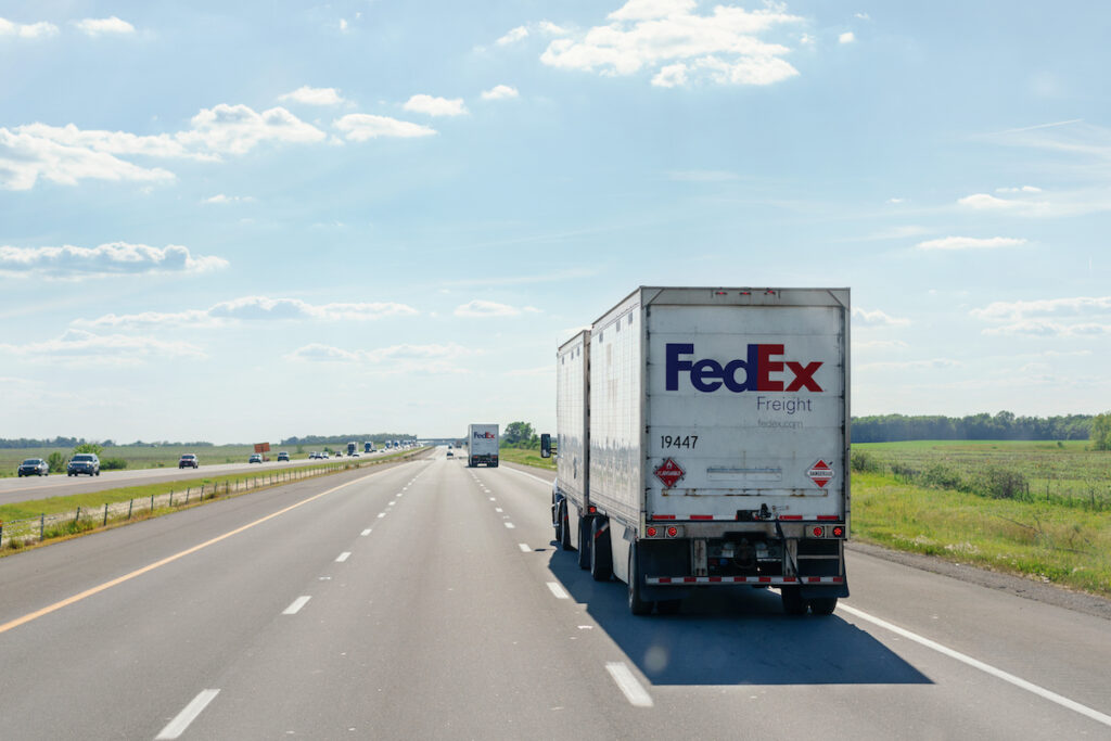 Rear-view of FedEx Freight delivery trucks driving on the highway