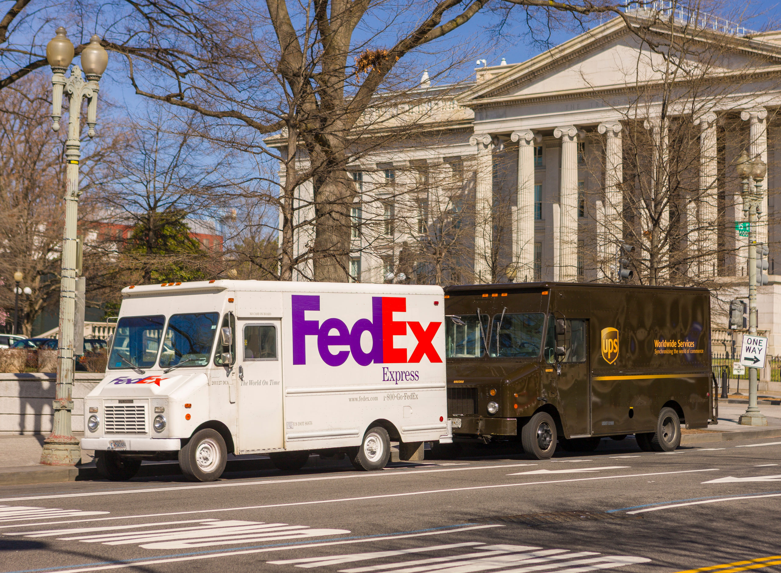 FedEx and UPS trucks parked on a street, image representing general rate increase hikes in 2023