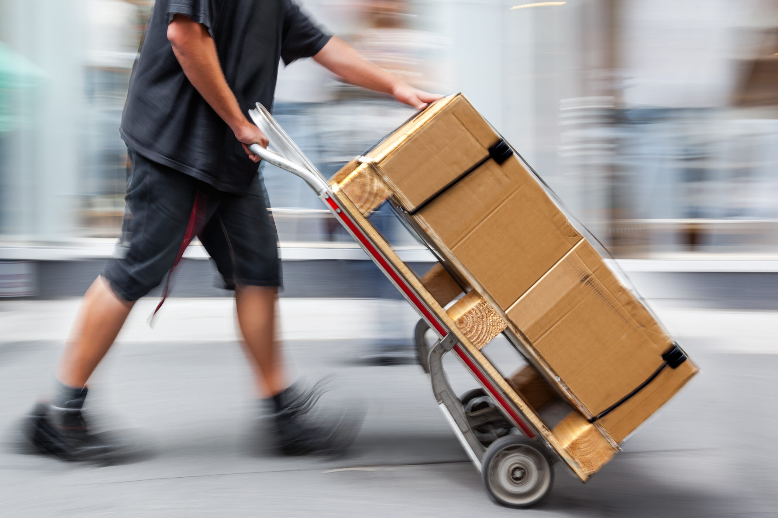 Parcel Delivery Driver Carriers Heavy Packages on Dolly