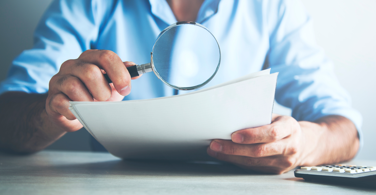 Professional reviewing invoices with magnifying glass