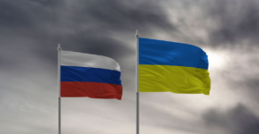 Russian and Ukrainian flags fly with dark stormy clouds in the background