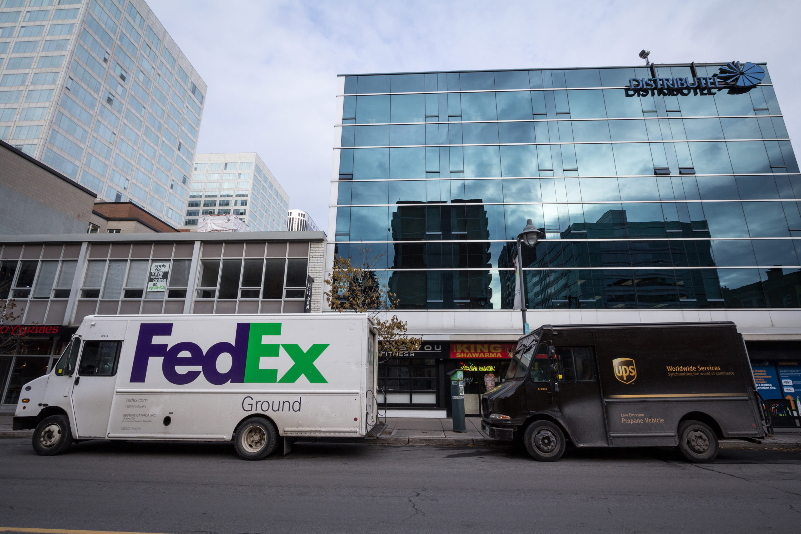 A FedEx and UPS trucks parked on the street in