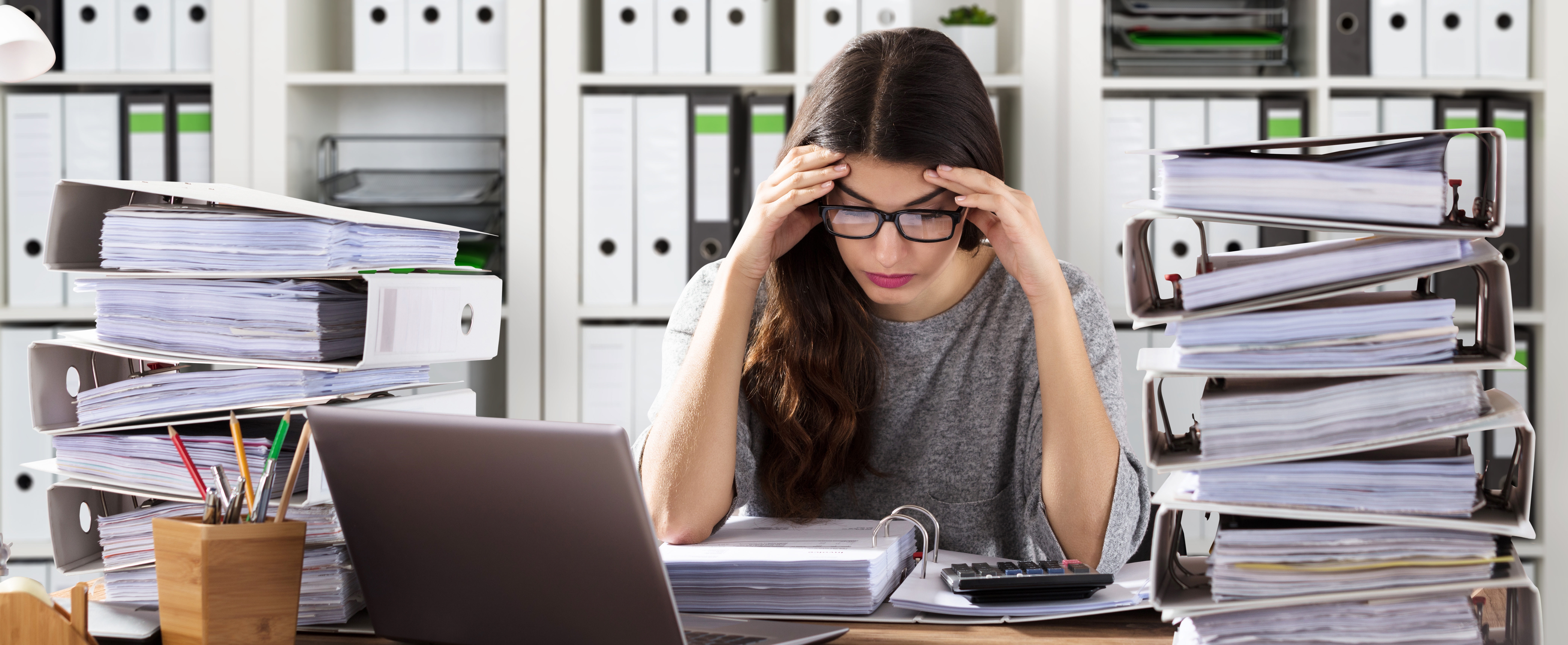 Woman looking stressed among stacks of invoices