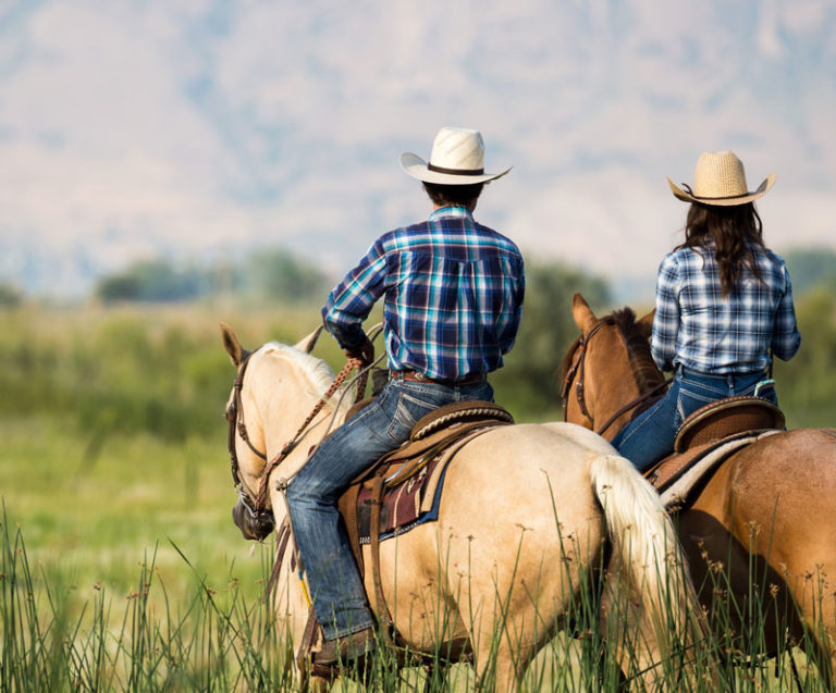 Two people on horseback wearing Cavender's cowboy hats