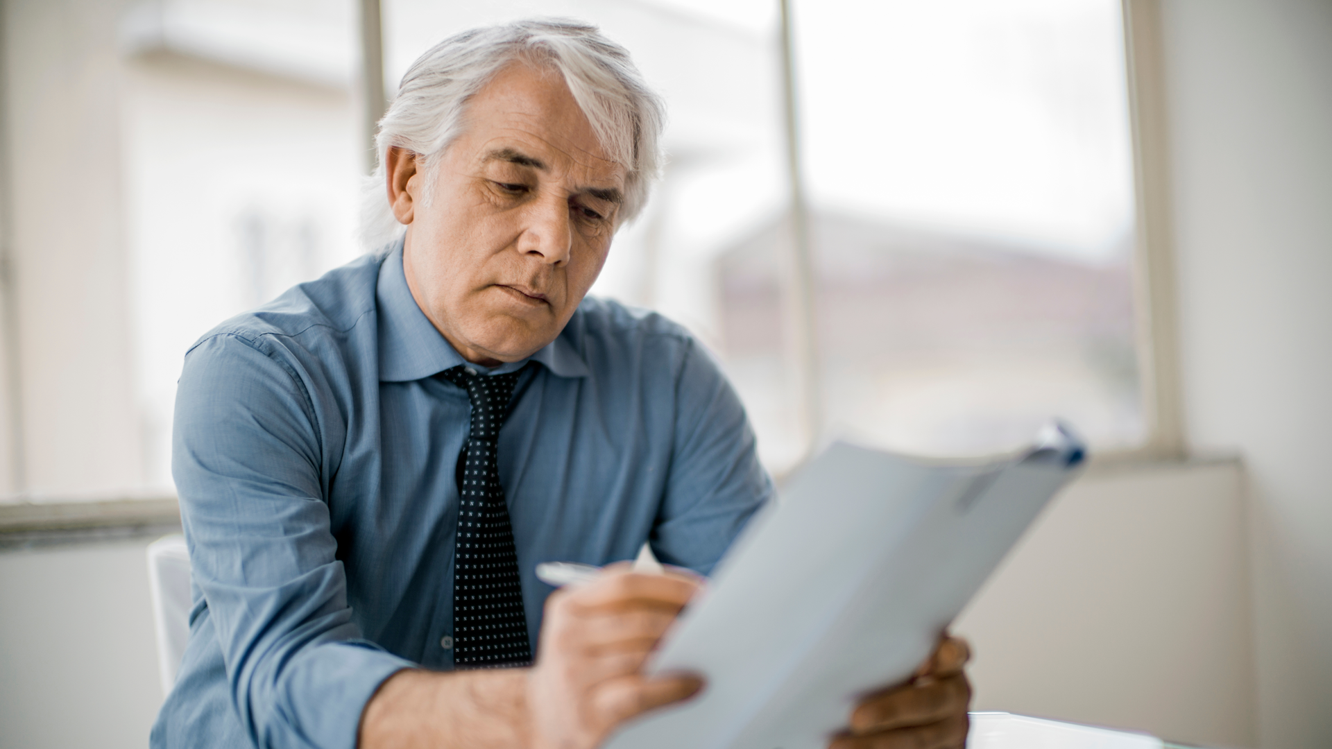 A man holding a piece of paper with pen in hand