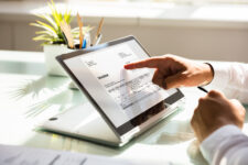 A person scrolls through an invoice on a tablet or laptop.