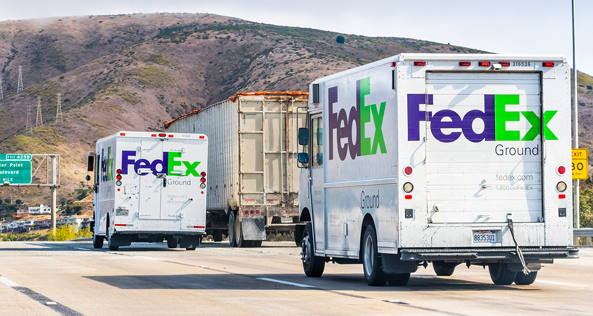 Two FedEx trucks driving down a busy highway
